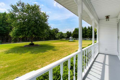 White porch looking out on a green backyard.