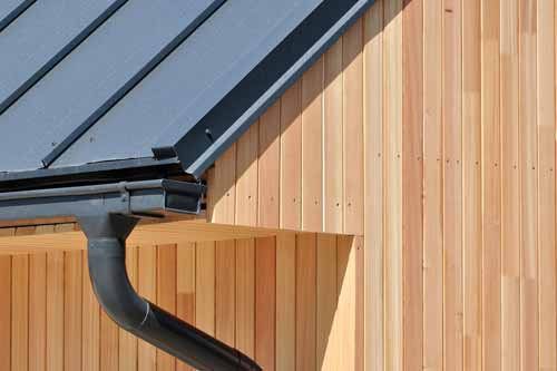 Gutters on a metal roof and wooden siding home.